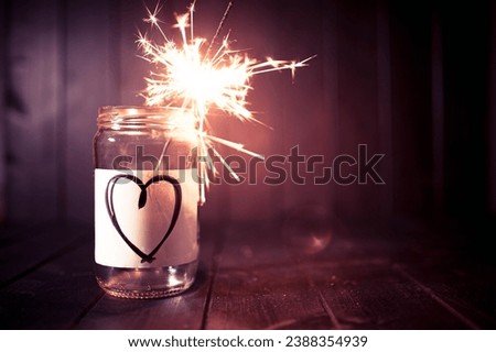 Hope for love, still life with glass jar with heart symbol and burning sparkler. Romantic pink tone. Background with copy space for Valentine.