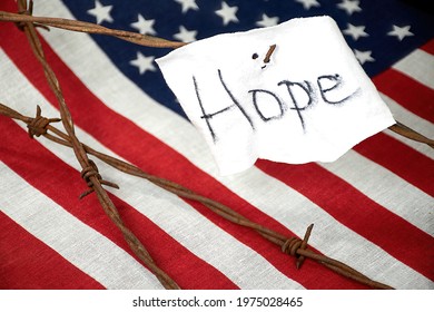 Hope Sign On Torn White Fabric On Rusty Barbed Wire Fence With American Flag Background