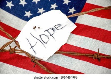 Hope Text On Torn White Fabric On Rusty Barbed Wire Fence With American Flag Background