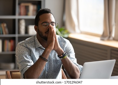 Hopeful African American male believer sit at desk pray to God ask beg for good luck, thoughtful biracial superstitious man hold hands in prayer feel grateful thankful, faith, religion concept - Powered by Shutterstock