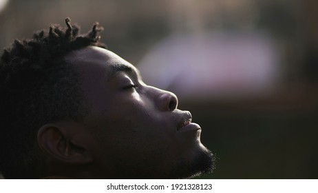 Hopeful African Man Looking Up At Sky, Black Person Closing Eyes In Meditation And Contemplation