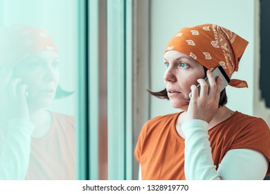 Hopeful Female Carpenter Talking On Mobile Phone While Looking Through The Window Of Her Small Business Woodwork Workshop