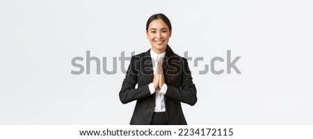 Hopeful glad asian businesswoman in black suit bowing politely and say namaste, greeting clients and smiling friendly. Thankful female manager thanking for help, being grateful, appreciate help.