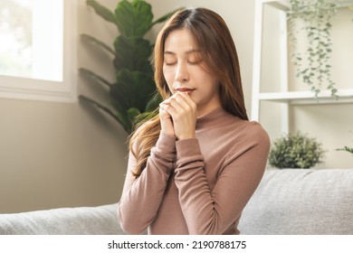 Hopeful Make Wish, Calm Asian Young Woman Belief, Hand In Prayer, Sitting Meditating On Sofa At Home, Christian Girl Praying To God For Ask, Request With Closed Eyes Dreaming For Help, Thank You God.