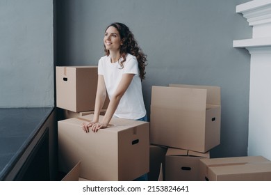 Hopeful Woman Is Packing Cardboard Box. Happy Hispanic Girl Purchasing Real Estate. Moving And Relocation To New Home. Independence, Changes And New Life Concept.