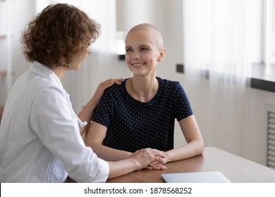 Hopeful Young Sick Woman Sit At Desk In Doctor Office Listen To Attending Physician Believe Trust Her. Happy Grateful Female Patient Talk To Oncologist At Meeting Feel Cancer Free Excited Of Recovery