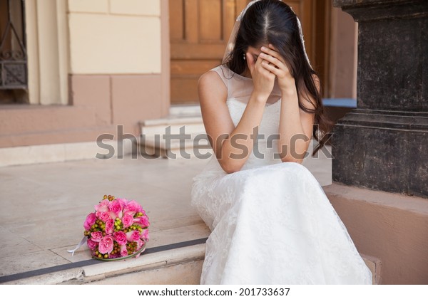 Hopeless bride crying outside a church after being\
stood up on her wedding\
day