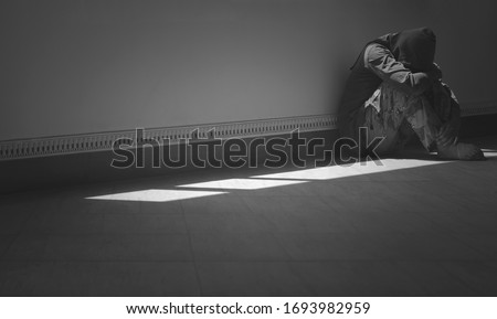 Hopeless Sad Man Sitting Alone with Hugging his Knees on the floor in the Corner of Room, Dark tone with Black and white style