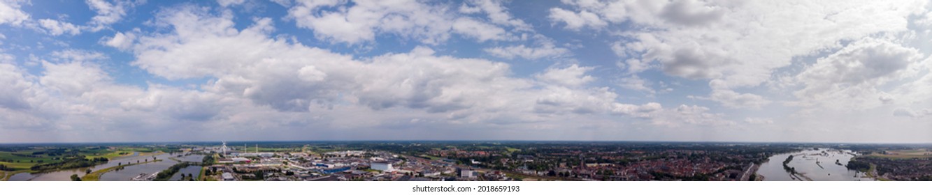 Horizon above Zutphen, The Netherlands, with cumulus clouds against a vibrant blue sky. Wide aerial weather condition panorama concept.