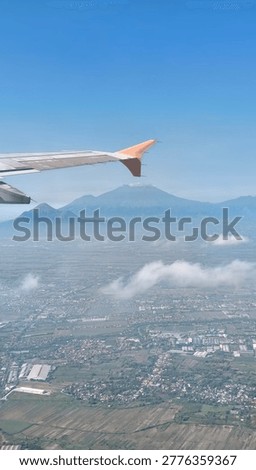 A horizon level view from an airplane window shows a bright blue sky, glowing sunlight, and distant mountains clearly visible, creating a perfect blend of sky, light, and nature at high altitude.