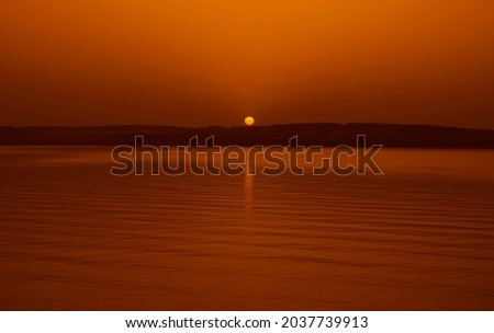 horizon line. hot sun rise sun set orange yellow light. reflection of sunlight on water surface. 