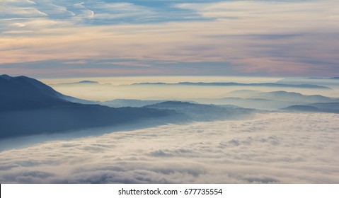 Horizon line in mountains with sea of fog during colorful sunset