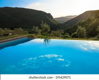 The horizon and reflections in an infinity swimming pool against a bright afternoon sky