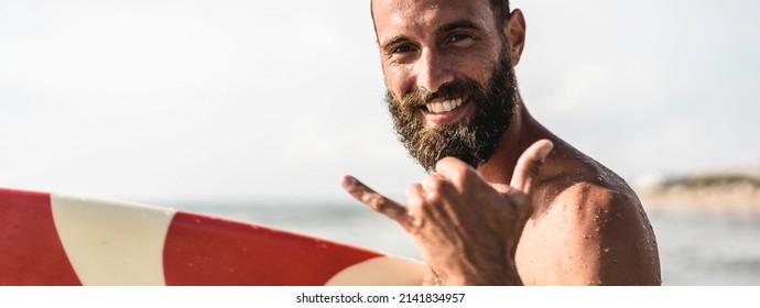 Horizontal banner or header with surfer happy with surf surfing smiling doing hawaiian shaka hand or hang loose sign for fun during surf session in ocean waves on beach vacation - Powered by Shutterstock