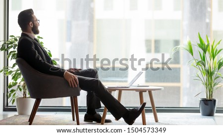 Horizontal banner middle eastern ethnicity businessman sit on armchair resting in modern room looks out window thinking about prosperous his own company plan future projects, business vision concept