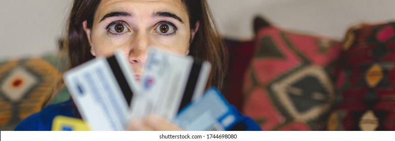 Horizontal Banner Scared Eyes And Worried Woman Because Too Much Expanses Or Internet Scam During Online Shopping. Student Holding Many Credit Cards. Debts, Technology, Home Banking Or Fraud Concept.