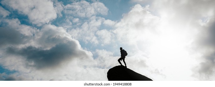 Horizontal Banner With Silhouette Of Man Standing On A Peak And Sky On Background With Copy Space.