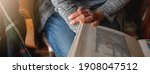 Horizontal banner unrecognizable woman holding a photo album sitting on the sofa. Memories concept.