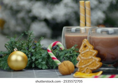 A horizontal Christmas photograph showing two clear glass cups filled with hot chocolate. Waffle sticks, candy canes, pine branches, nuts and anise complete the festive picture. - Powered by Shutterstock