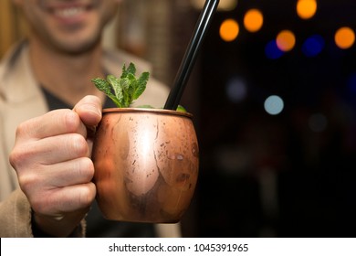 Horizontal Close Up Of A Man  Holding A Moscow Mule Cocktail, Served In A Copper Mug , With Focus On The Drink. 