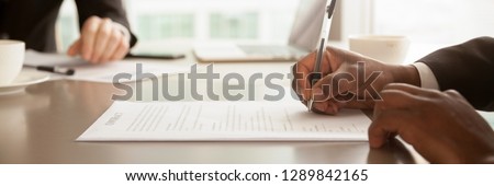 Horizontal close up photo african businessman sitting at desk holds pen signing contract paper, lease mortgage, employment hr or affirm partnership agreement concept, banner for website header design