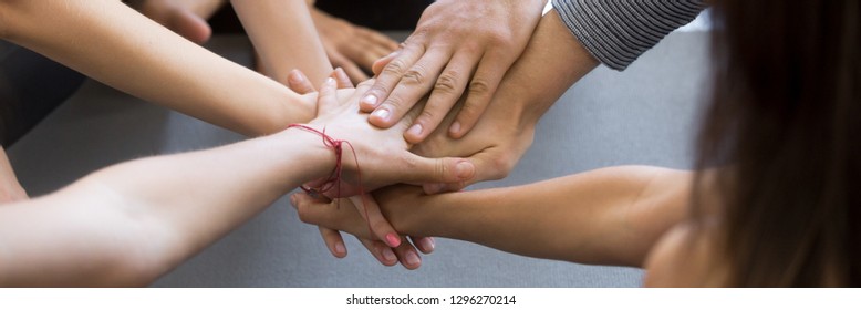 Horizontal close up photo young people girls and guys hold stack hands together high five gesture symbol of support trust and common goal teamwork and success concept, banner for website header design