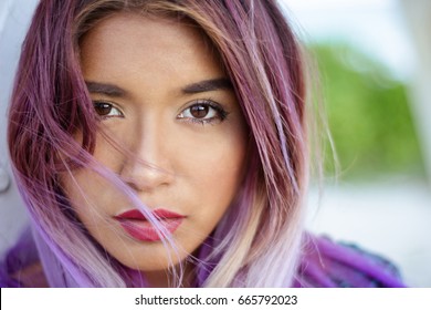 Horizontal Close up portrait of mexican young woman looking at the camera with her hair over her face and looking serious at the camera.