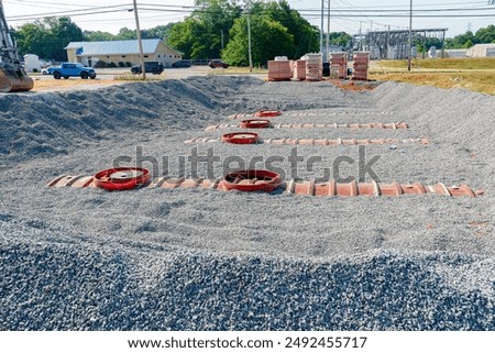 Horizontal close-up shot of four partially buried underground fuel storage tanks at new gas station convenience store construction.