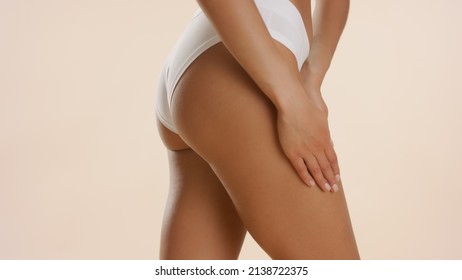 Horizontal close-up shot of good-looking slim female model in white underwear strokes her hip on beige background | Unwanted body hair removal concept - Powered by Shutterstock