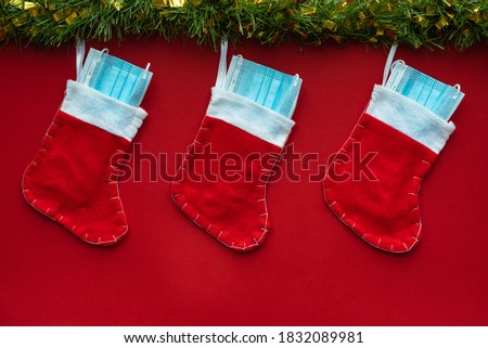 Horizontal color image with an overhead view of a christmas decoration with Coronavirus on a red background, christmas socks, face masks and hydroalcoholic gels. Covid concept on christmas.