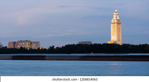 Horizontal composition covering the Mississippi River waterfront barge traffic and the State Capitol of Louisiana at Baton Rouge