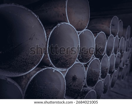 Horizontal composition of stacked PVC pipe circles in low light, highlighting industrial texture, geometry, and repetition.