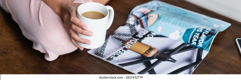 Horizontal Crop Of Woman Holding Cup Of Coffee Near Magazine On Table