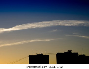 Horizontal dramatic cloudscape over industrial silhouette buildings background