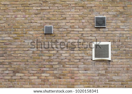 horizontal front view of air conditioning vents of different sizes on brick wall