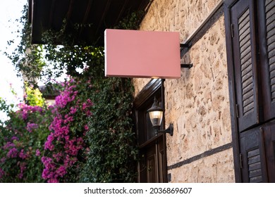 Horizontal front view of empty pink square signage on a building with classical rustic architecture