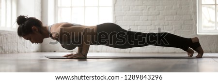 Horizontal full length side view photo young sporty woman wearing activewear doing yoga four limbed staff exercise chaturanga dandasana workout at home or sport center banner for website header design