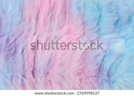 A horizontal, full-frame macro view displays a soft, long-haired faux fur texture with a pastel color gradient blending from blue and purple to pink