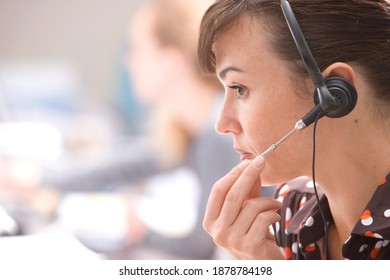 Horizontal Head And Shoulder Profile Shot Of A Stressed Young Woman Adjusting Her Headset At Desk In Office With Copy Space.