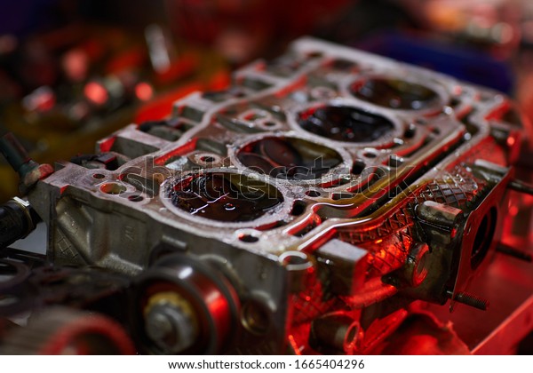 Horizontal high angle close up\
conceptual shot of car engine part with oil in red light, copy\
space