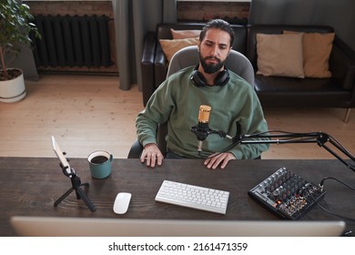 Horizontal High Angle Medium Portrait Of Modern Young Middle Eastern Blogger Sitting At Desk Watching Something For Reaction Video