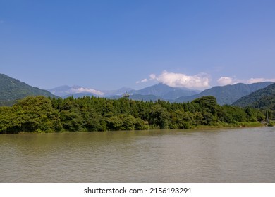 Horizontal image of the clouds above the mountains, river rapids, green forest at the Dujiangyan Irrigation System, Dujiangyan, Sichuan, China, blue sky, copy space for text, UNESCO World heritage