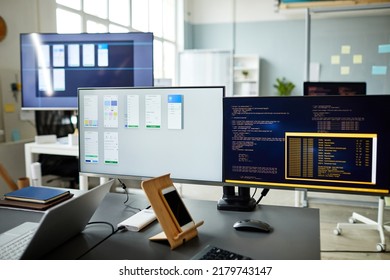 Horizontal image of computer monitors with programs and computer codes on monitors standing on workplace of programmer