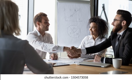 Horizontal image different ethnicity businessmen shaking hands sitting at conference room desk starting negotiating solving common issues planning future cooperation, company boss greet client concept