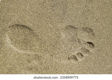 Horizontal image. Footprint in the sand. Sandy beach. Summer. Imprint. Relaxation. Vacation. Holiday. Tracks. Walking. Lake. Shore. Seashore. Barefoot. Background.