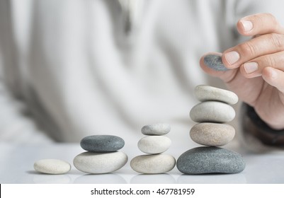 Horizontal image of a man stacking pebbles on a table with copyspace for text. Concept of risk management and wealth.