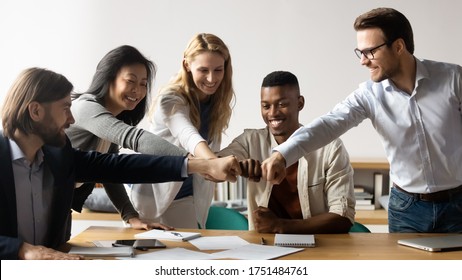 Horizontal image middle-aged and young five multiracial staff members gather in boardroom show unity stacked hands in circle, fists bumping symbol of togetherness common goals business loyalty concept