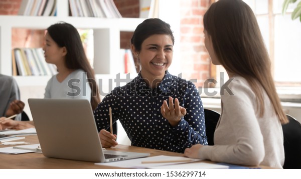 Horizontal image multiracial students seated\
inside of modern classroom divided into pairs do shared task,\
indian ethnicity schoolgirl explain thoughts to mate girls thinking\
together teamwork\
concept