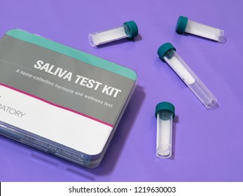 A Horizontal Image Of A Saliva Test Kit From A Laboratory And Four Test Tubes (collection Tubes) On A Purple Background.