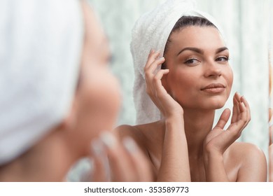 Horizontal image of a self-confident brunette looking at her reflection - Powered by Shutterstock